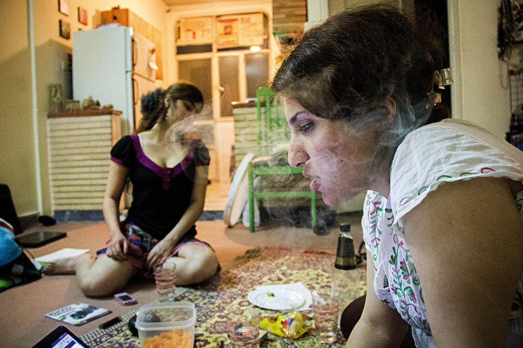 from right Yasmin using her laptop to check Facebook and smoking, Negar is drunk and smoking too.