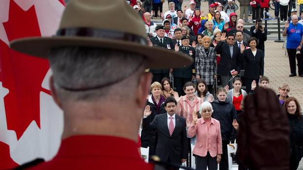 A Royal Canadian Mounted Police officer raises his hand as a group of 60 people take the oath of citizenship during a special Canada Day citizenship ceremony in Vancouver, B.C., on Sunday July 1, 2012. (DARRYL DYCK/The Canadian Press)