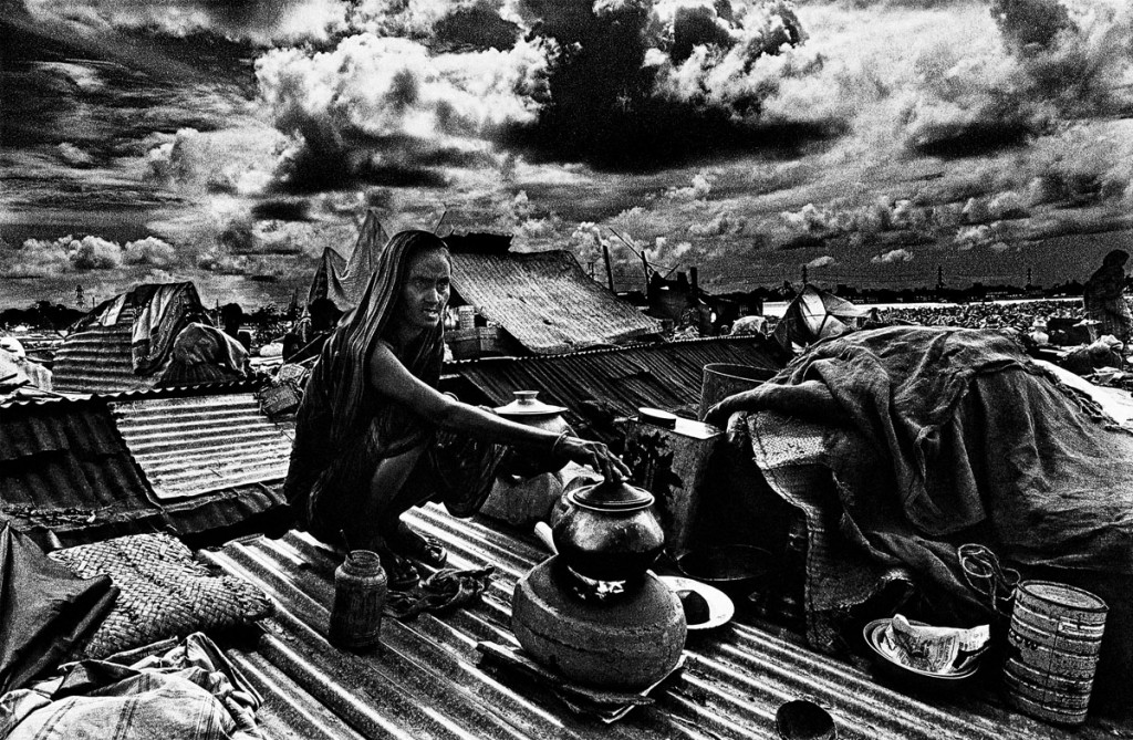 Woman cooking on the rooftop of her house during floods. 1st September 1988. The water went up another three feet. ? Shahidul Alam/Drik/Majority World