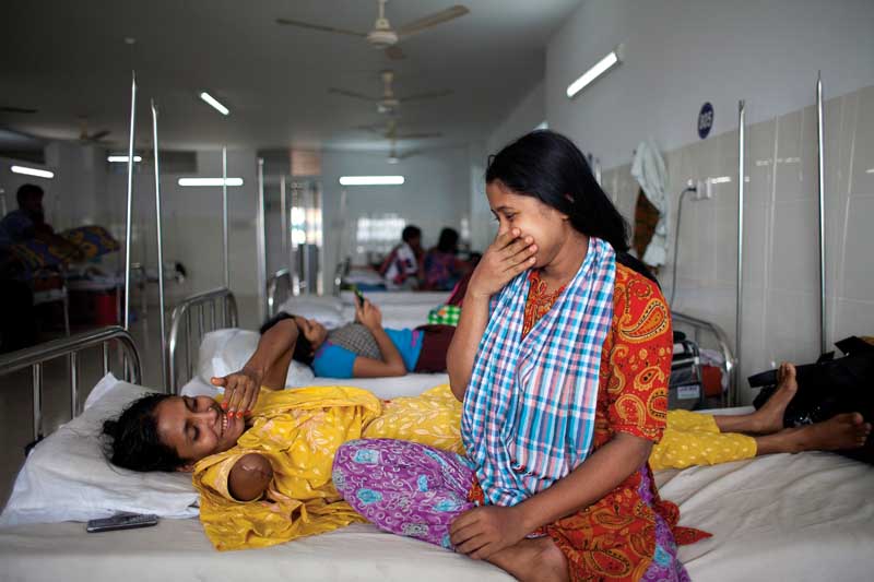 Mariyam, whose right arm had to be amputated to free her from underneath the Rana Plaza rubble, shares a joke with her sister, Enam Medical College Hospital, Savar, Dhaka. June 19, 2013. Photo ? Suvra Kanti Das